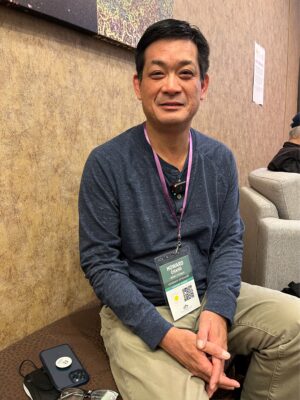 Man, indoors, smiling and holding up name tag