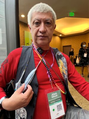 Man, indoors, with grey hair red shirt and vest