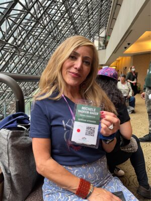 Woman, indoors, with blond hair and holding up name tag