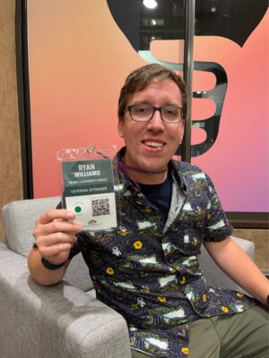 Man, indoors, with glasses, smiling and holding up name tag