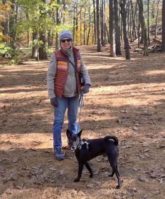 A person walking a dog on a trail in the woods