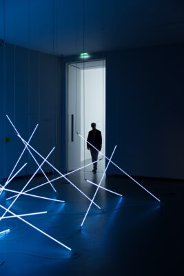 Person entering dark room with neon beams from bright hallway