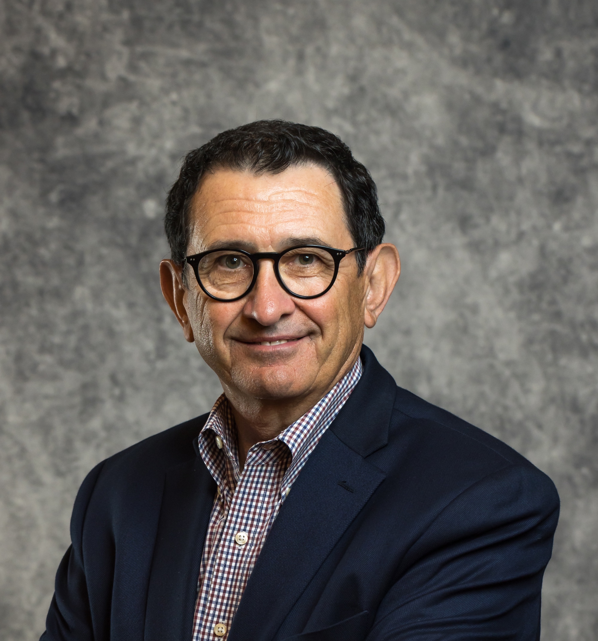 Man with black hair and glasses smiling