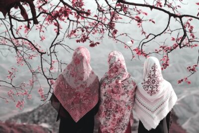 Three women wearing head scarves sitting on hill