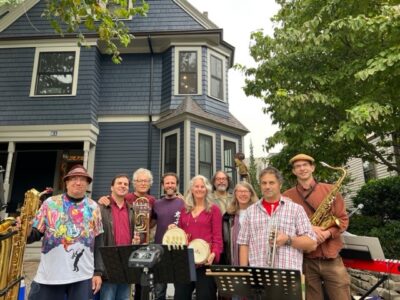 Band standing in front of house