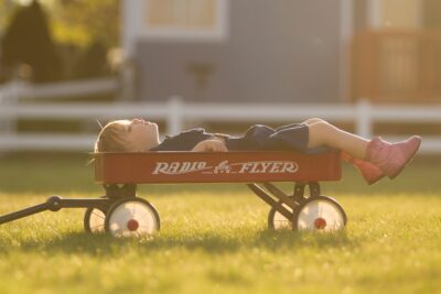 Young person lying in a red wagon