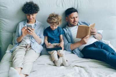 Three people reading on a bed